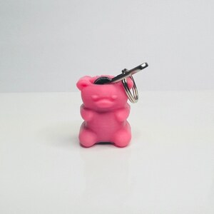 Op de afbeelding: Roze gummy bear sleutelhanger met een zilveren sleutelring. De gummy bear is hol en heeft een klein muntje erin.