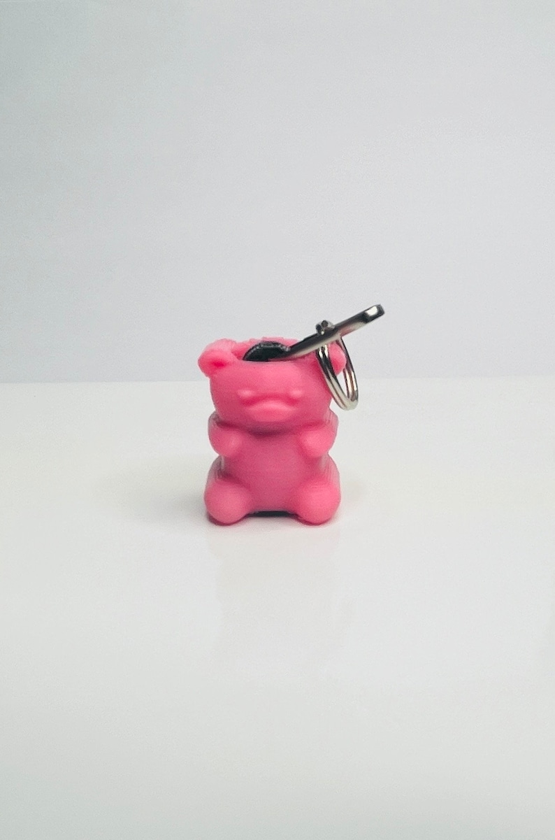 Op de afbeelding: Roze gummy bear sleutelhanger met een zilveren sleutelring. De gummy bear is hol en heeft een klein muntje erin.