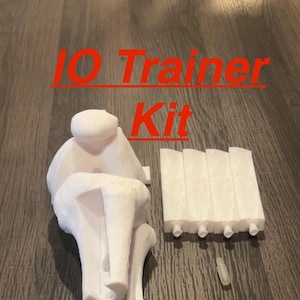 May include: A white plastic 3D printed model of a human knee joint, with the text "10 Trainer Kit" in red letters above it.