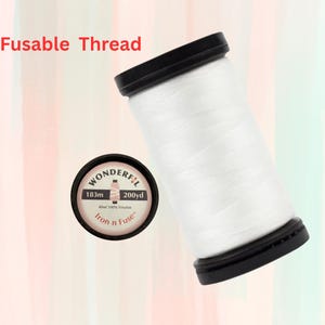 May include: White fusible thread spool with a label that reads "Wonderfil 183m 200yd All 100% Polyester Iron n Fuse"