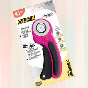 May include: Pink and black rotary cutter with a self-retracting blade. The packaging features the brand name OLFA and the text "Endurance" and "Ergonomic".