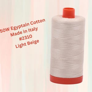 May include: A spool of 50 weight Egyptian cotton thread in light beige. The spool is labeled "50W Egyptian Cotton Made in Italy #2310 Light Beige".