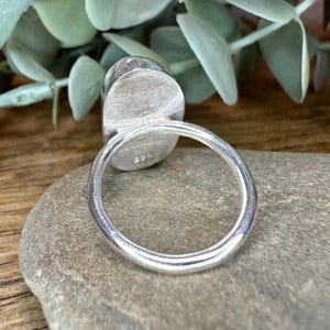 May include: Silver ring with a large oval shaped gemstone. The ring is marked with the number "925" on the inside of the band.