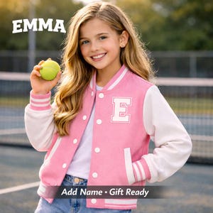 Puede incluir: Chaqueta universitaria rosa y blanca con la letra "E" en la parte delantera. La chaqueta tiene mangas blancas y un cuello blanco. El texto "EMMA" está encima del sujeto y el texto "Add Name • Gift Ready" debajo.