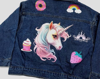 May include: A blue denim jacket with colorful iron-on patches. The patches include a unicorn, a donut, a rainbow, a cupcake, a castle, and a strawberry.