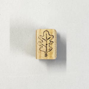 May include: A wooden stamp with a carved oak leaf design.