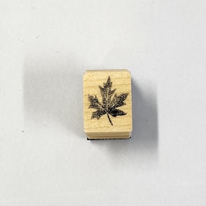 May include: A wooden stamp with a black maple leaf design.