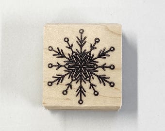 May include: A wooden stamp featuring a black snowflake design.