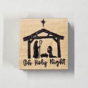 Könnte beinhalten: Ein Holz-Stempel mit einer Silhouette der Weihnachtsgeschichte und dem Text "Oh Holy Night".