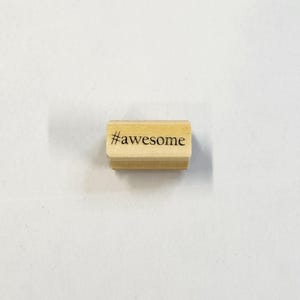 May include: Wooden stamp with the text "#awesome" on it.