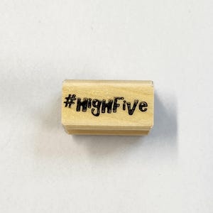 May include: Wooden stamp with the text "#HighFive" in black ink.