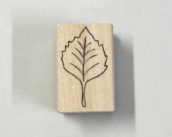 May include: A wooden stamp with a black outline of a leaf.