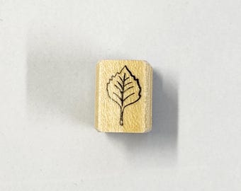May include: A wooden stamp with a black outline of a leaf.