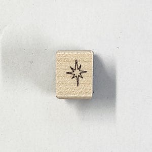 May include: A wooden stamp featuring a starburst design.