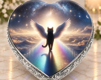 May include: A heart-shaped keepsake box with a silver-toned metal border featuring an intricate embossed pattern. The lid displays a graphic of a black cat with large white wings standing on a rainbow path against a starry night sky background.