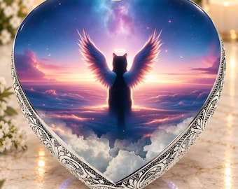 May include: A heart-shaped decorative plaque featuring a central image of a black cat with large white wings and a glowing halo, set against a vibrant sunset sky filled with clouds. The border is crafted from silver-toned metal with intricate scrollwork.