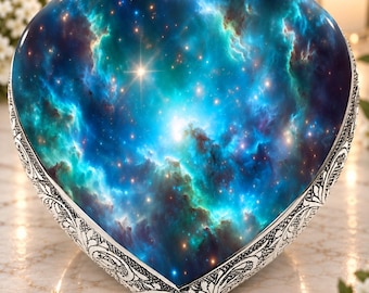 Puede incluir: Una caja de recuerdos en forma de corazón con un estampado de nebulosa en tonos azul profundo, verde azulado y morado, acentuado por estrellas blancas. Los bordes del corazón están enmarcados por un borde de metal plateado con relieves florales.