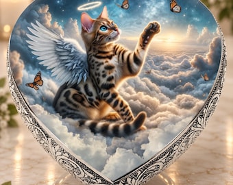 May include: A heart-shaped plaque featuring a tabby cat with white feathered wings and a glowing halo, sitting amidst clouds at sunset. The cat reaches toward orange butterflies in a starry sky. The plaque has an ornate, metallic silver border.