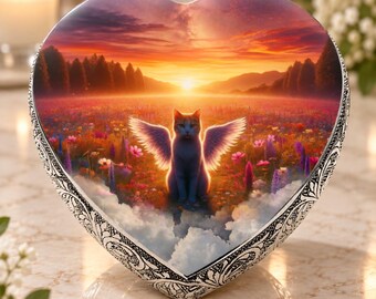 May include: A heart-shaped decorative box featuring a silver-toned metal frame with intricate embossed scrollwork patterns. The center displays a vibrant sunset scene over a flower field with a winged cat sitting in the middle of the landscape.