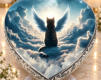May include: A heart-shaped decorative plaque featuring a central image of a dark tabby cat with large, feathered wings sitting amidst a bright, cloudy sky. The border of the heart is crafted from silver-toned metal with an intricate embossed pattern.