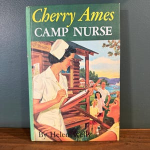 Vintage hardcover book is "Cherry Ames, Camp Nurse" (Book 19) by Helen Wells