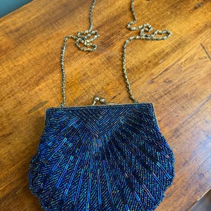 Elegante bolso vintage La Regale azul con cuentas en forma de concha y cadena larga dorada.