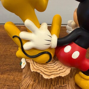 K&ouml;nnte beinhalten: Eine Disney-Figur mit Mickey Mouse in roten Shorts und schwarzen Handschuhen und Pluto in Gelb. Der Sockel ist ein Baumstumpf mit den Disney- und China-Marken.
