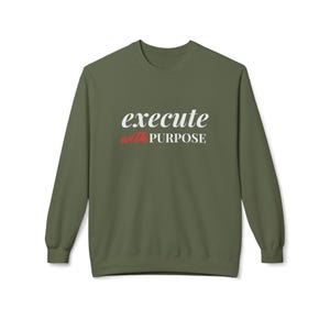 Könnte beinhalten: Ein grüner Langarmsweatshirt mit dem Text "execute with PURPOSE" in weißer und roter Schrift.