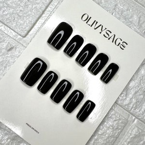 May include: A set of ten black press-on nails with a subtle curved design. The nails are displayed on a white card with the text "OLIVYSAGE" and "PRESS ON NAILS".