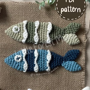 May include: Two crocheted fish ornaments, one in shades of green and one in shades of blue, each featuring white wavy stripes, a white button eye with a dark cross, and a textured tail. A circular graphic in the corner reads PDF pattern.