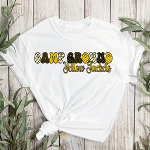 May include: White t-shirt with the text "Campground Yellow Jackets" in black and gold letters with a patterned design.