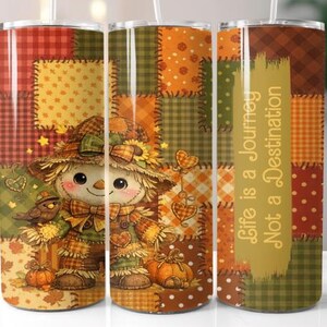 May include: A tumbler featuring a patchwork design with a scarecrow illustration. The scarecrow has a straw hat and bow tie, with pumpkins and a bird. The tumbler has the text "Life is a Journey Not a Destination".