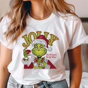 Könnte beinhalten: Weißes T-Shirt mit einem grünen Cartoon-Charakter, der einen Weihnachtsmannhut trägt und ein Glas Rotwein hält. Das Wort "JOLLY" steht über der Figur, darunter der Satz "But It Could Be the Wine".