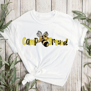 May include: White t-shirt featuring a yellow and black bee graphic and the text "Campground" in yellow lettering.