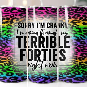 May include: A stainless steel tumbler with a rainbow leopard print design. The tumbler has a white background with the text "Sorry I'm Cranky, I'm going through my TERRIBLE FORTIES right now".