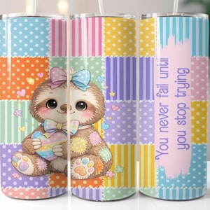 May include: A stainless steel tumbler featuring a cartoon sloth holding a rainbow heart. The tumbler has a patchwork design with polka dots and stripes in various colors. Text on the tumbler reads "You never fail until you stop trying."