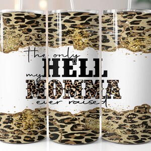 Könnte beinhalten: Ein weißer Becher mit Leopardenmuster und goldenen Glitzerakzenten. Der Text "The only hell my momma ever raised" ist auf den Becher gedruckt.