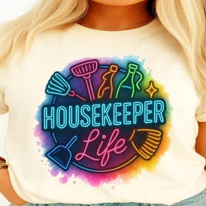May include: A white t-shirt with a colorful graphic design of cleaning supplies and the text "Housekeeper Life".