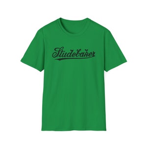 Könnte beinhalten: Ein grünes T-Shirt mit einem schwarzen "Studebaker"-Logo in einer Vintage-Baseball-Schrift.