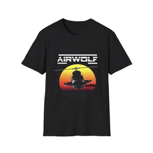 May include: Black t-shirt with a white graphic of a helicopter flying in front of a sunset with the text "AIRWOLF" above it.