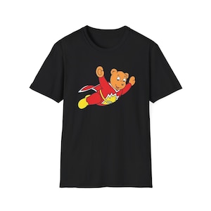 May include: Black t-shirt with a cartoon image of a brown bear wearing a red superhero costume and flying.