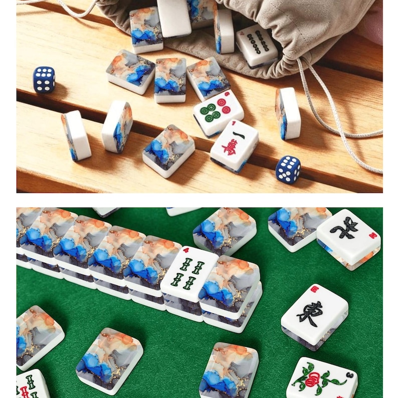May include: A set of Mahjong tiles featuring a white face with black, red, and green symbols, and a back side with a blue, orange, and white marbled pattern. The set includes two blue dice with white dots and a beige drawstring storage bag.