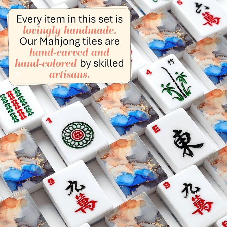 May include: A collection of white Mahjong tiles featuring traditional red, green, and black characters alongside tiles with abstract blue, orange, and gold ink patterns. A text box reads: Every item in this set is lovingly handmade. Our Mahjong tiles are hand-carved and hand-colored by skilled artisans.