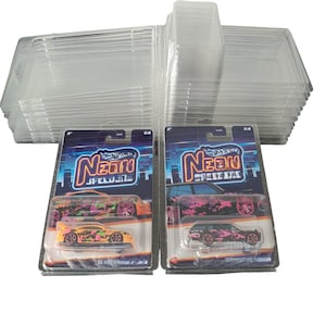 May include: Two clear plastic display cases with Hot Wheels cars inside. The cars are both black with pink and orange camouflage paint. The cars are labeled "Neon Street Life".