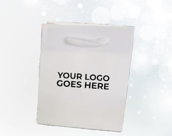 May include: A white paper gift bag with a handle. The text "YOUR LOGO GOES HERE" is printed in black on the front of the bag. The bag is rectangular and has a simple, clean design, suitable for branding.