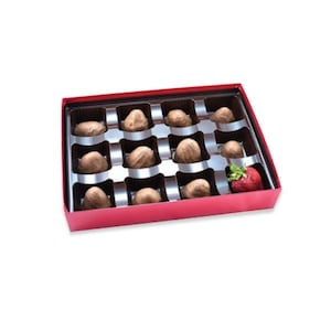 May include: A red box filled with chocolate covered strawberries. The box has a clear plastic insert with 12 individual compartments. A single strawberry is visible outside the box.