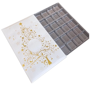 May include: A white cardboard advent calendar with a gold tree design and numbers 1 through 25. The calendar is open to reveal a gray plastic tray with 24 compartments.