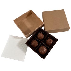 May include: A brown cardboard box with a lid, containing a four-compartment tray of chocolate candies. The tray is made of dark brown plastic and the candies are arranged in the compartments.