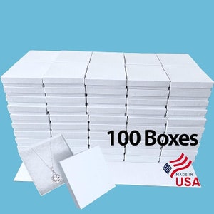 May include: One hundred white cardboard boxes stacked in a rectangular formation. The boxes are all the same size and are arranged in a grid pattern. The boxes are made in the USA. A single box is shown open with a silver necklace inside.