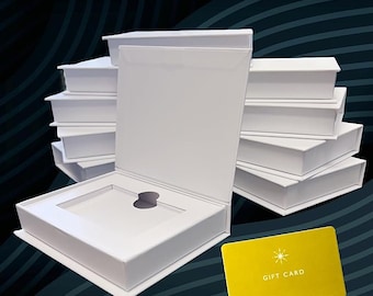 Puede incluir: Una caja de regalo blanca con una ranura para una tarjeta de regalo. La caja está abierta y el interior es visible. La caja está sobre un fondo con estampado blanco y negro. Una tarjeta de regalo amarilla con el texto "Gift Card" es visible en primer plano.